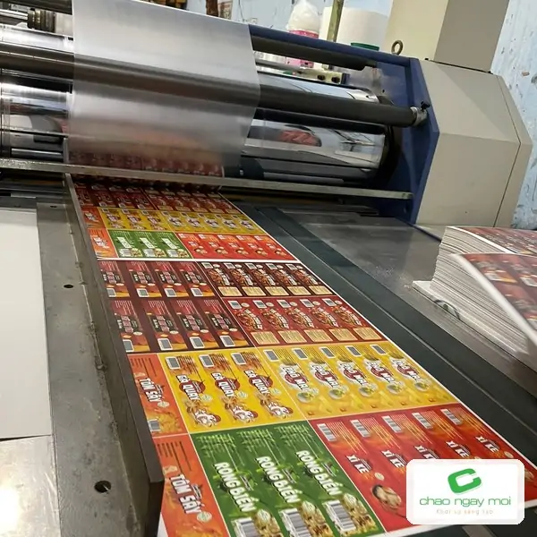 Tờ in đang đi qua máy cán màng công nghiệp