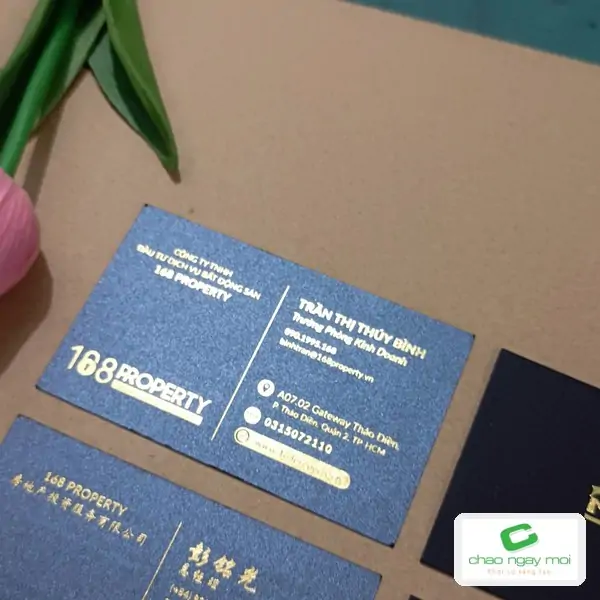 Danh thiếp ép kim vàng với chữ và logo sắc nét trên nền xanh đậm